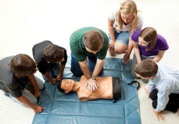 teenagers learning CPR on a dummy