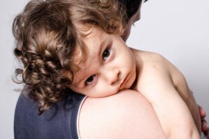 Parent holding unwell child who is sad