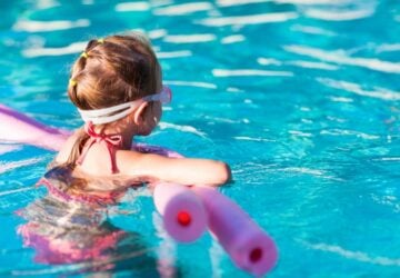 Swimming pool, girl with goggles and pool noodle