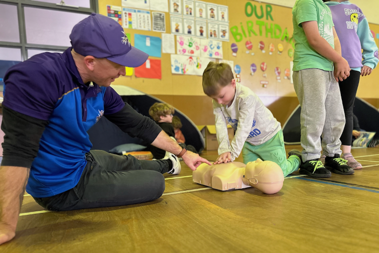 Students Save Lives child practicing chest compressions on dummy.