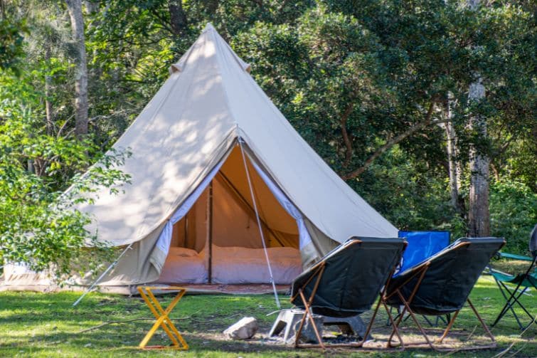 A glamping tent with two chairs and table outside.