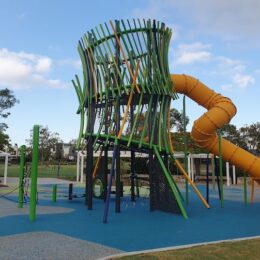 Large green and yellow play tower with yellow tunnel slide at North Lakes Town Park at Lake Eden.