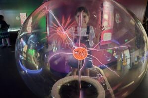 Young girl touching the plasma globe at SparkLab at the Queensland Museum.