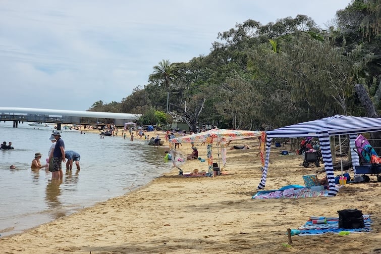Shelters and people on the beach at Coochiemudlo Foreshore East Park on Coochiemudlo Island.