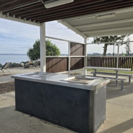 BBQ's and picnic tabes under a shelter by the water at Redcliffe Parkour Park.