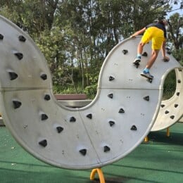 Boy climbing curved bouldering wall at Redcliffe Parkour Park.