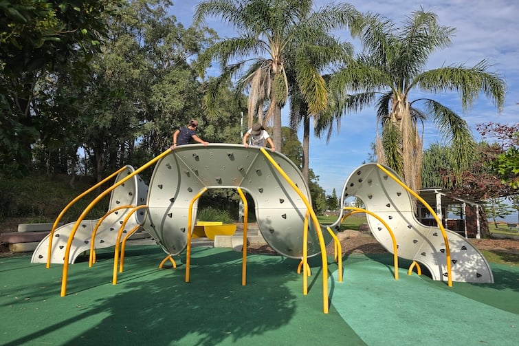 Kids climbing curved bouldering wall at Redcliffe Parkour Park.