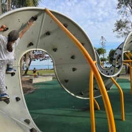 Girl climbing curved bouldering wall at Redcliffe Parkour Park.