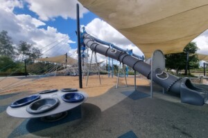 Spinning carousel and tunnel slide at Flagstone Adventure Playground.