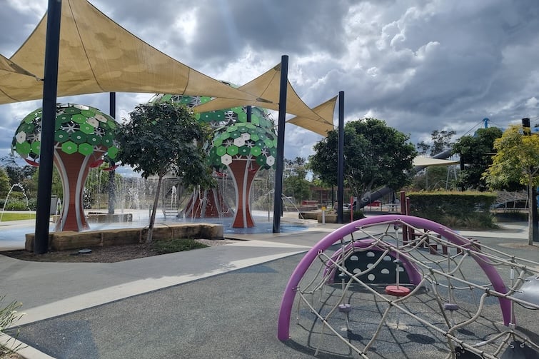 Climbing net at Flagstone Adventure Playground with view of Flagstone Water Park.
