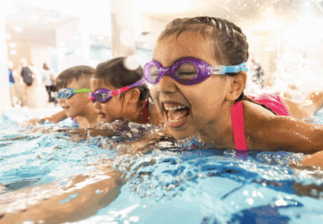 Carlile Swim smiling young swimmers kicking.