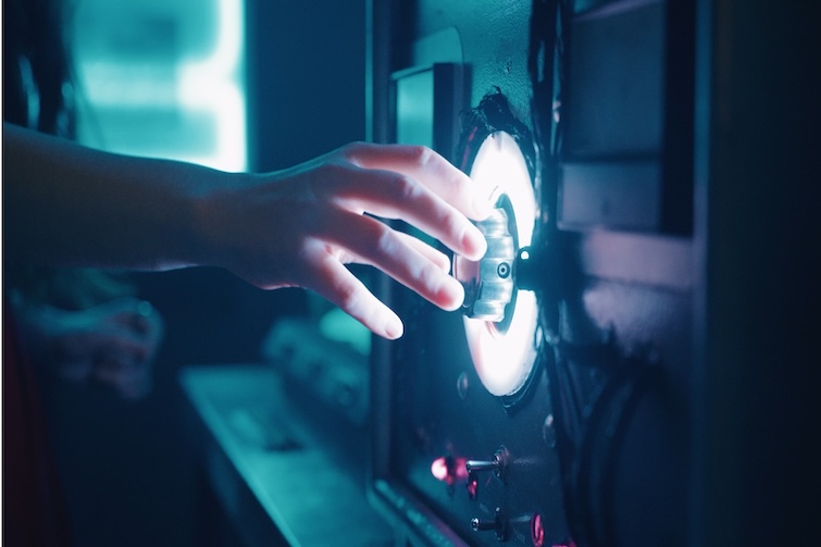 A hand touching a lit button at Project Immersive Escape Rooms.