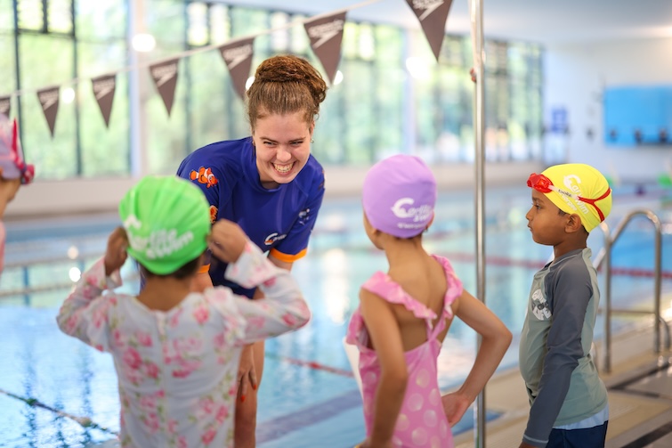 Swim teacher standing in front of children near a pool at Carlile Swim.