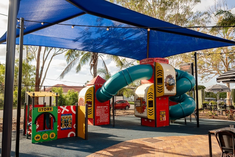 Outdoor playground with shade sail at Mansfield Tavern.