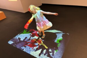 Child dancing on interactive floor display at LightPlay, Ipswich Art Gallery.