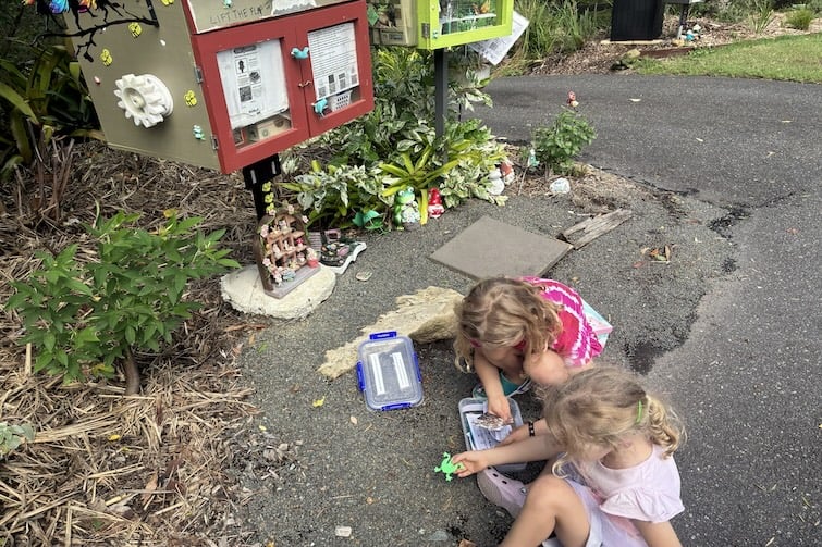Two children looking at geocache containers at Froggy Creek.