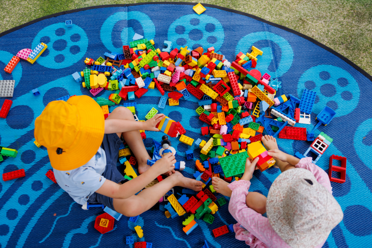 Lady Gowrie playing with blocks on outdoor mat.