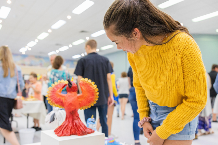 a girl looking at a phoenix art sculpture