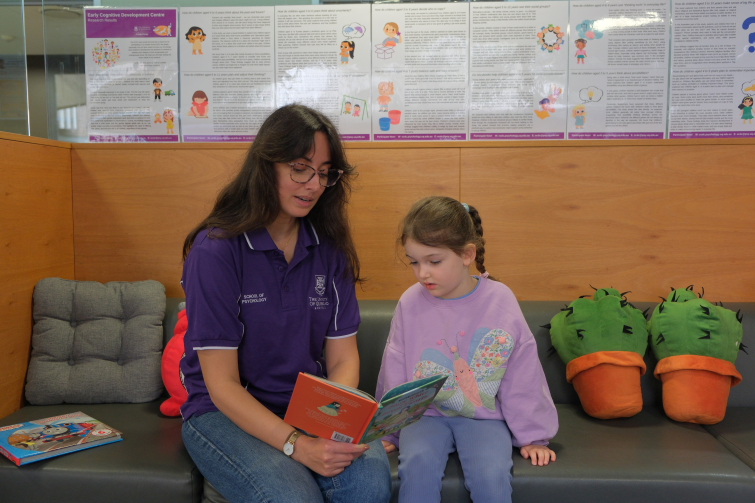 UQ Early Cognitive Development Centre staff reading with young girl.