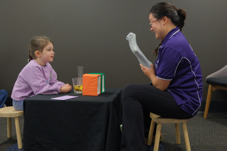 UQ Early Cognitive Development Centre staff with sock puppet and young girl.