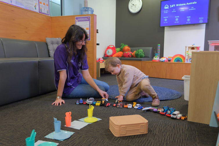 UQ Early Cognitive Development Centre staff with young boy and toy cars.