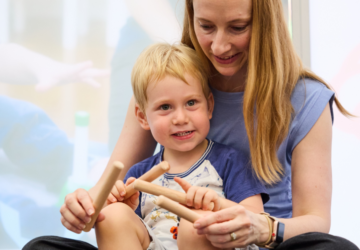 RAMSR teacher with child and rhythm sticks.