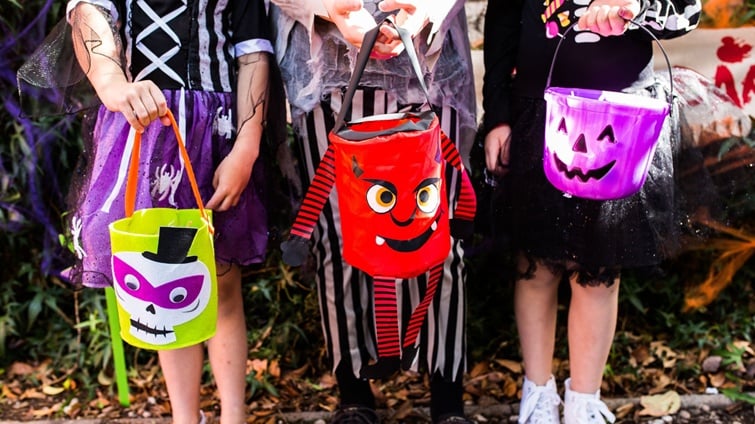 kids in halloween costumes carrying halloween baskets