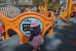 Little girl at play panels at The Hills District All Abilities Park.